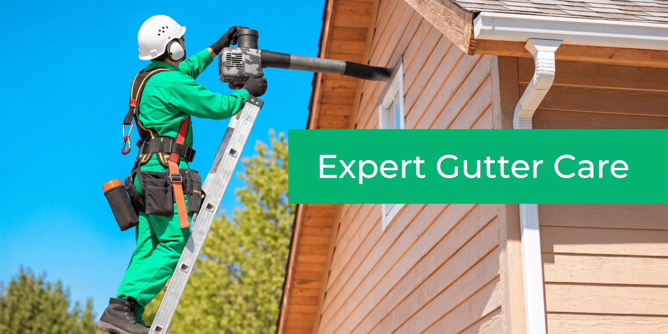 A professional construction worker in protective gear on a ladder cleaning house gutters with a blower.