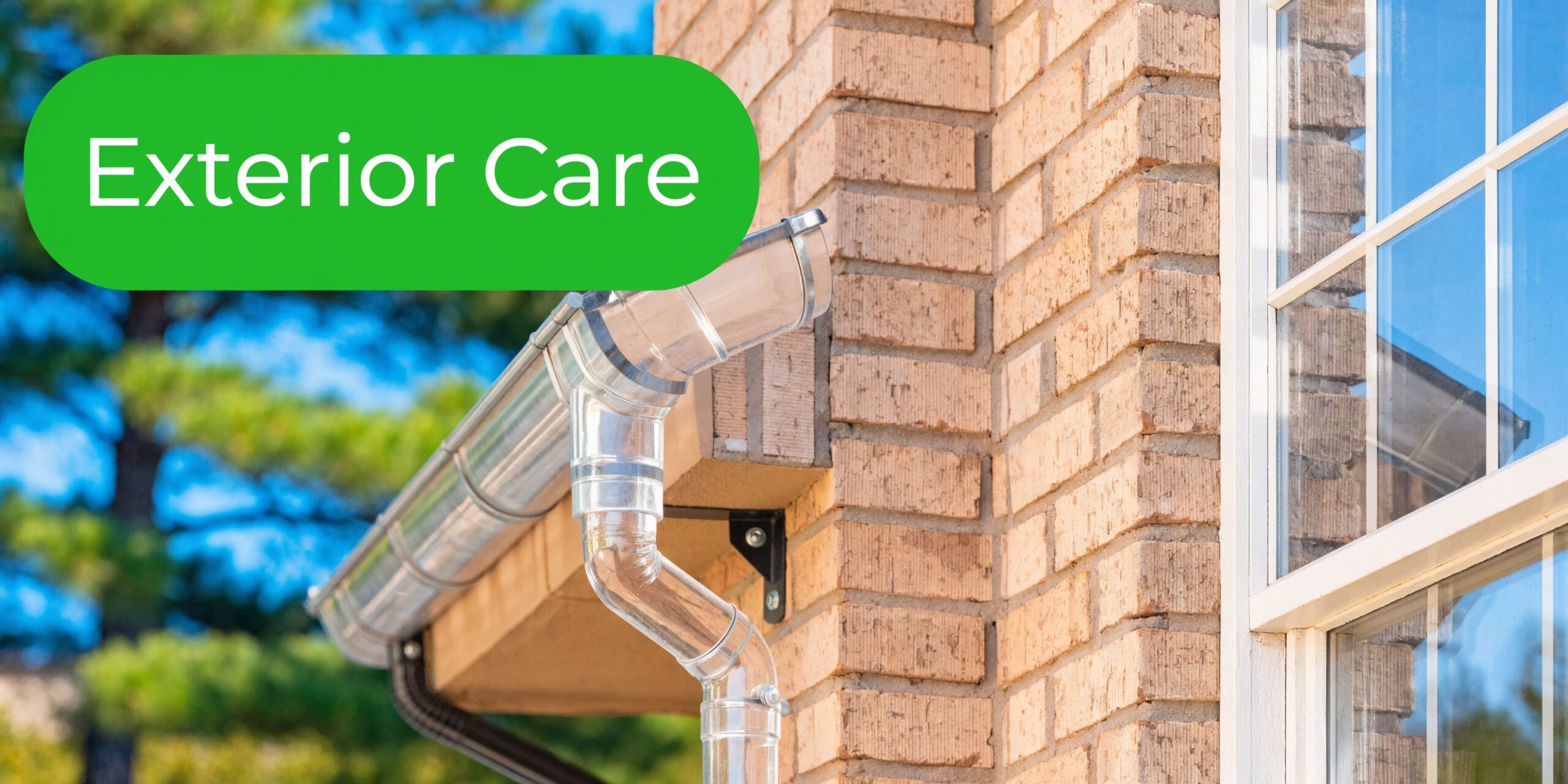 A close-up of a house exterior featuring a metal gutter system mounted against a textured brick wall.