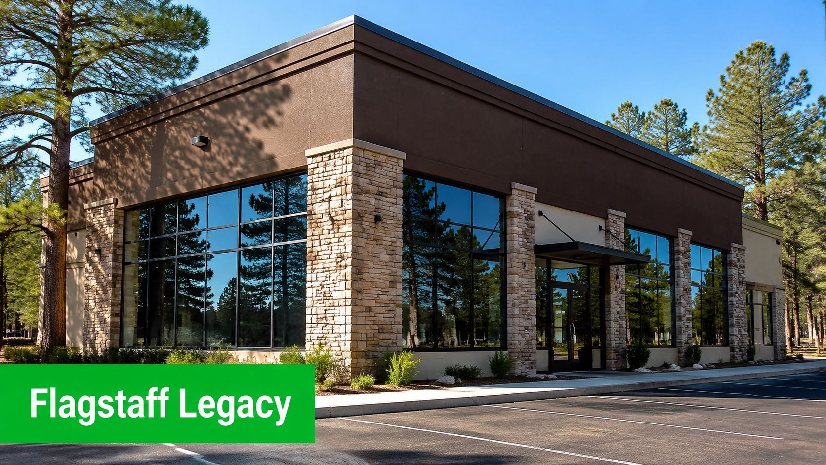 A modern commercial office building with large glass windows and stone accents in a forest setting.