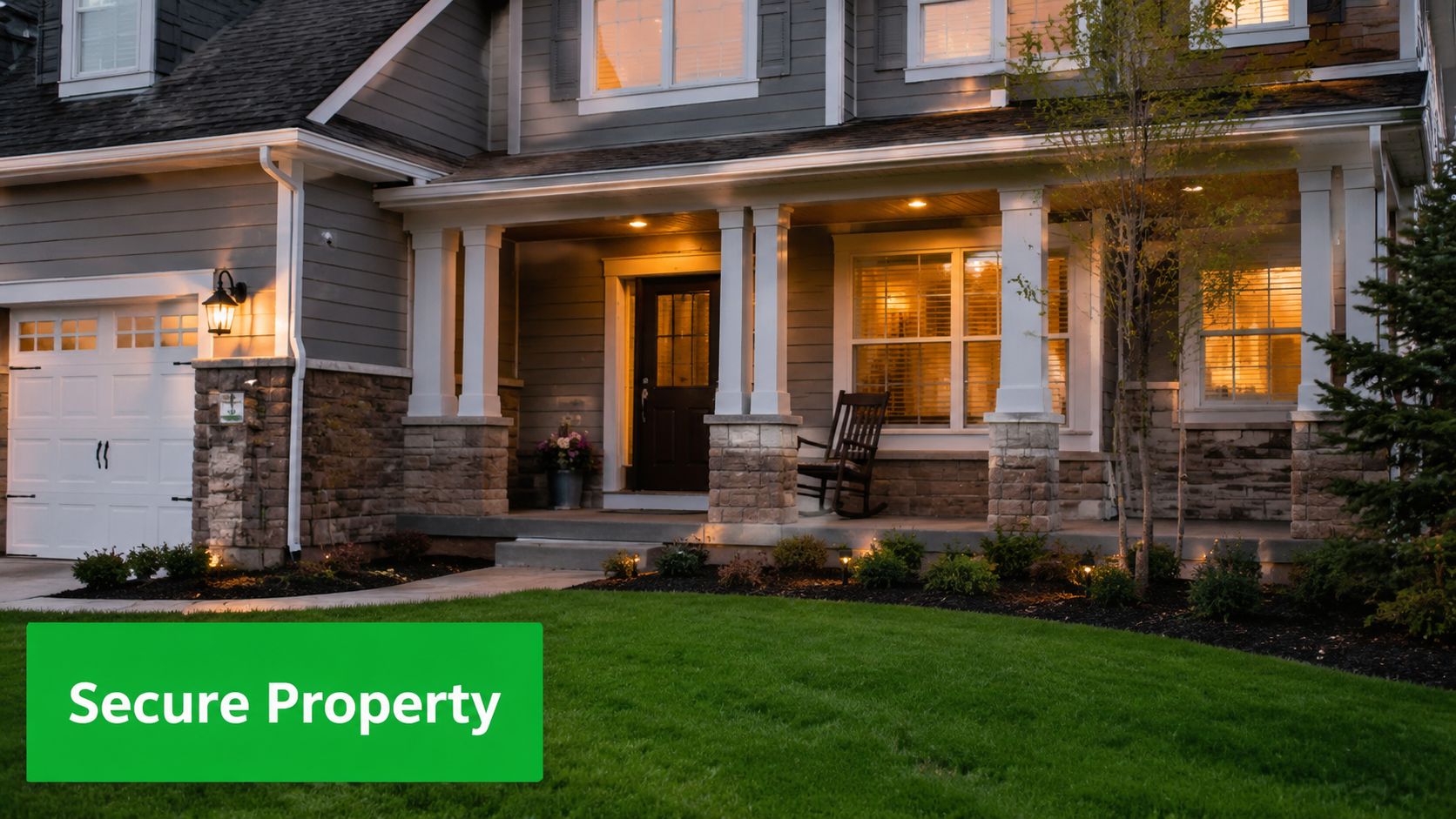 A well-maintained suburban home exterior with a glowing porch light and tidy landscaping at twilight.